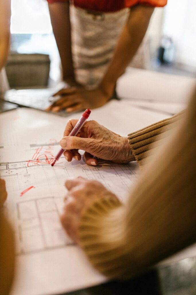 Hands working on office blueprints during a collaborative business meeting.