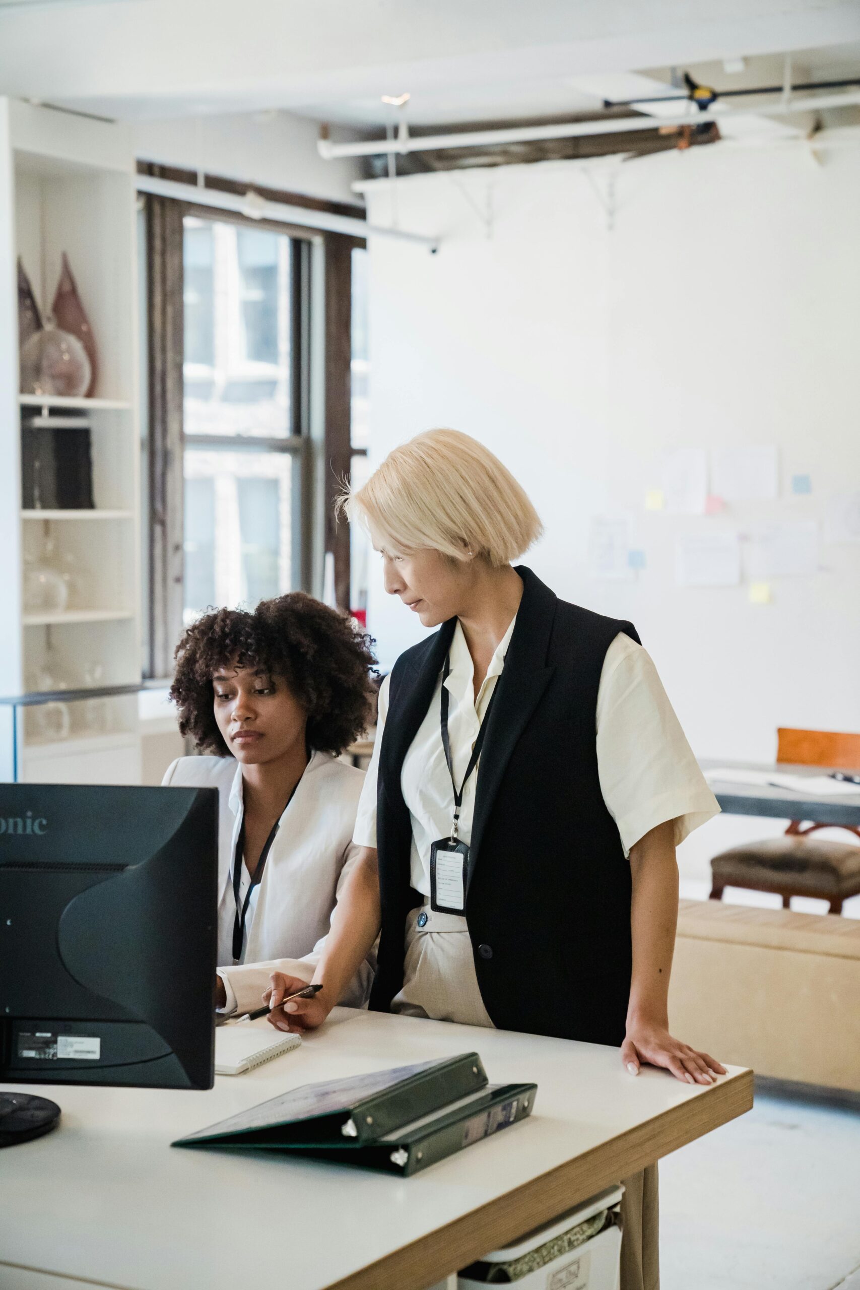 Two women collaborating on a project in a bright, modern office setting.